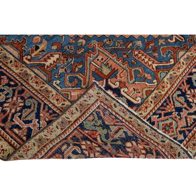 Beautiful antique Heriz hand-knotted wool rug with a rust field. This Heriz rug has a navy blue frame and multi-color...