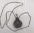 An intriguing vintage snuff or perfume bottle necklace featuring an ornate, silver-tone metal flask richly embellished...