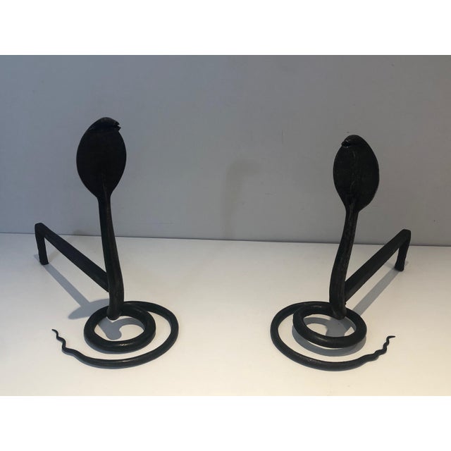 This beautiful pair of andirons with cobras is made of hammered wrought iron. It is a French work in the style of Edgar...