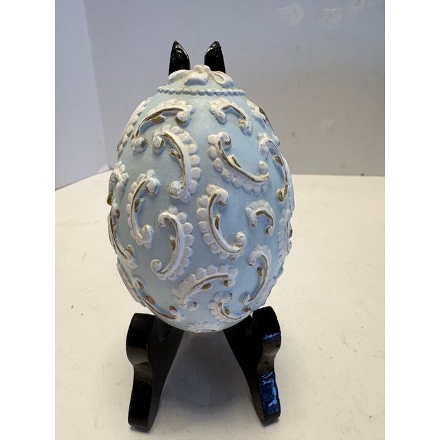 Hand-painted vintage chalkware egg featuring a delicate robin and holly motif, finished in soft blue with raised...