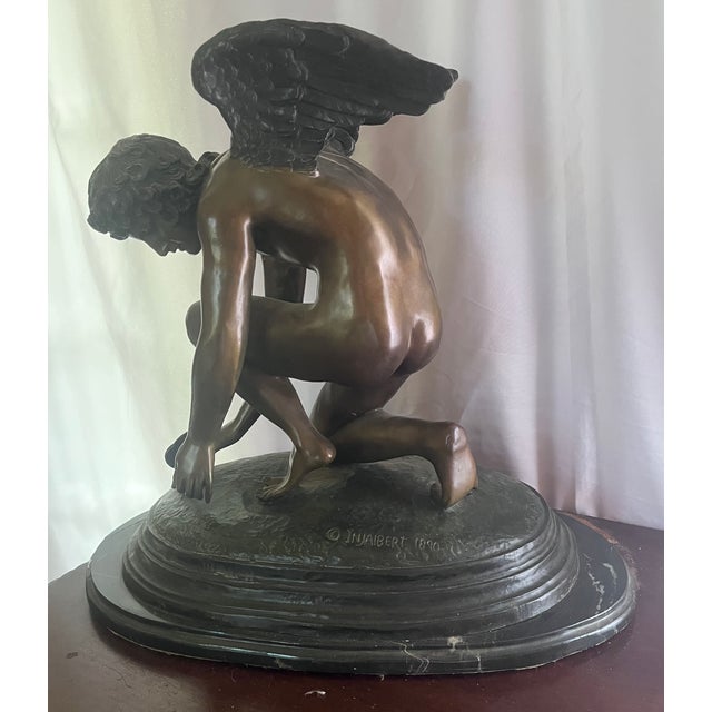 This is a late 19th-century bronze sculpture titled "Cupid Playing with a Butterfly," featuring a patinated bronze figure...