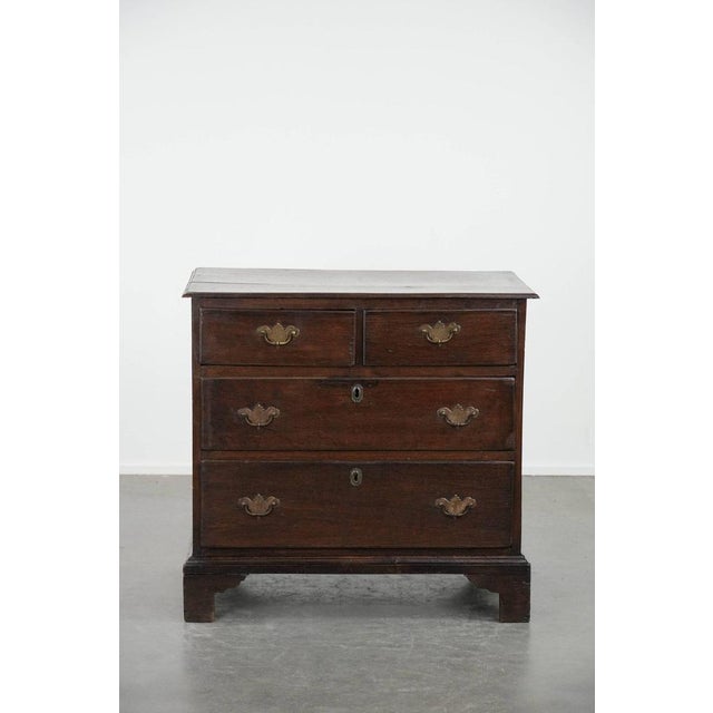 We are offering this subtle English antique oak chest of drawers from the 18th century in a beautifully modest size with a...