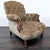 This vintage lounge chair features a soft, tufted velvet fabric in a warm brown tone and beautifully carved wooden...