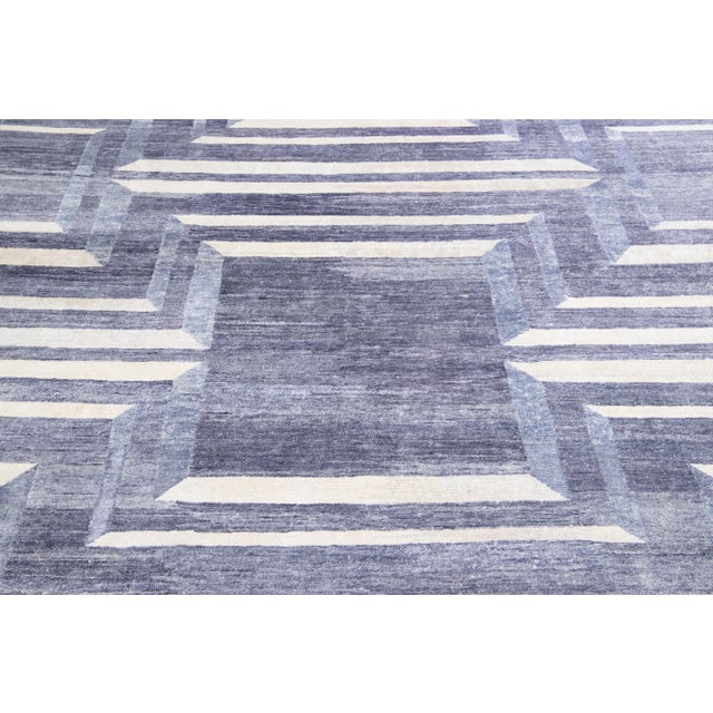This wool and silk rug boasts a striking contemporary design featuring a captivating geometric motif in an elegant grey...