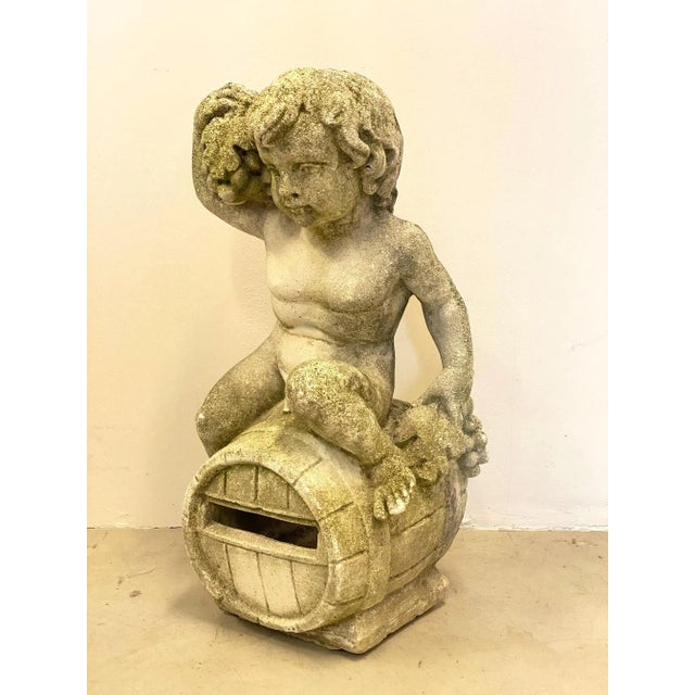 Garden sculpture made of cement from the 70's, it represents a putto with grapes sitting on a wine barrel, a metaphor for...