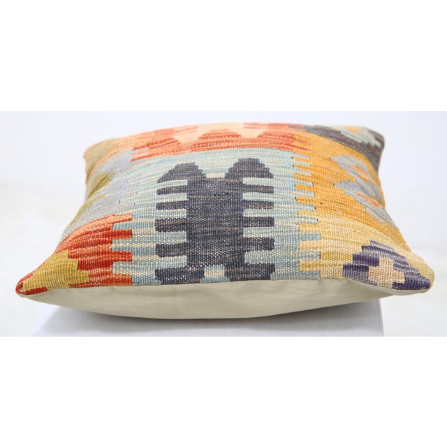 A one-of-a-kind handwoven Afghan wool kilim accent pillow featuring tribal comb-and-figure motifs in burnt orange on gray....