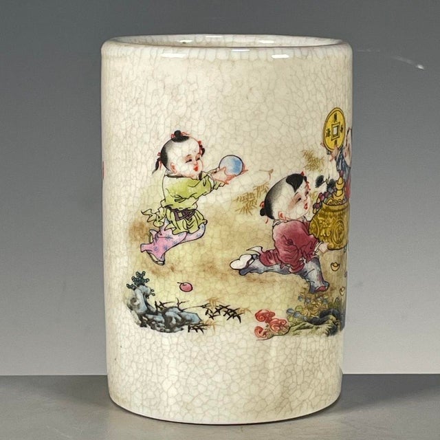 A charming Chinese porcelain brush pot (bitong). The cylindrical vessel features a creamy, all-over crackle glaze and is...