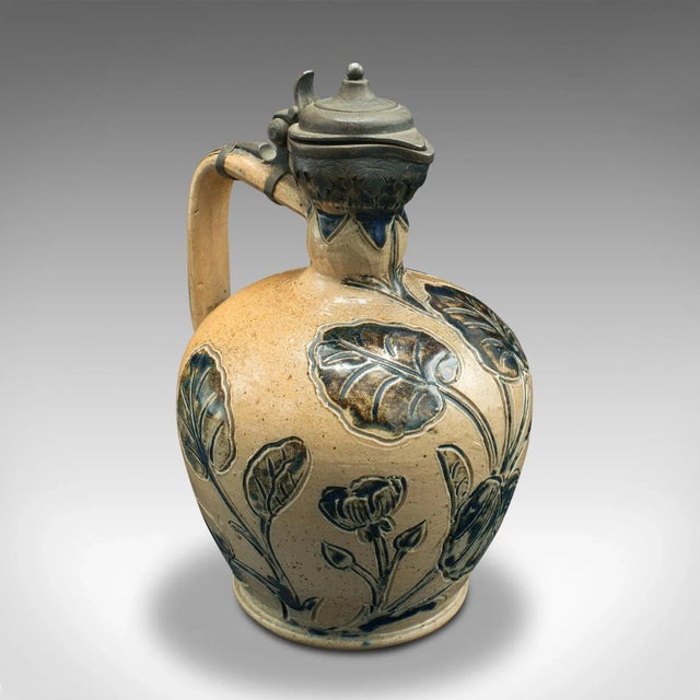 This is an antique decorative flagon. An English, ceramic and silver art pottery jug by Arthur Barlow for Doulton, dating...