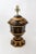 Vintage tole trophy lamp, painted in black and gold color. Leaf reliefs adorn the top and bottom of the lamp, and a man...