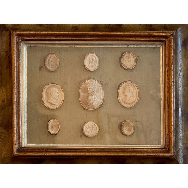 A rectangular framed group of intaglios arranged in a symmetrical layout, with a larger central oval surrounded by smaller...