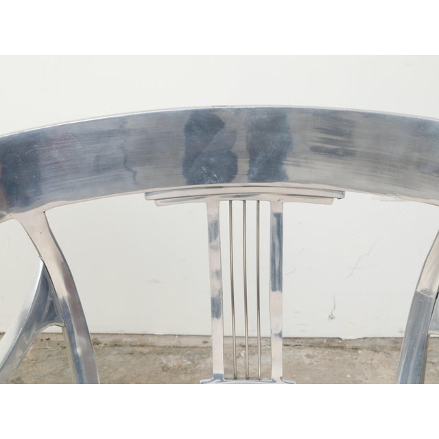 A pair of vintage steel armchairs from the mid-20th century, with curving backs, pierced splats and custom cushions....