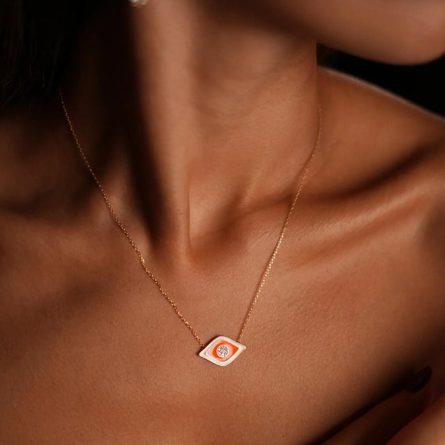 Make a bold statement with the Vivid Orange Enamel Evil Eye Pendant Gold & Diamond Necklace. Crafted with 18k gold plating...
