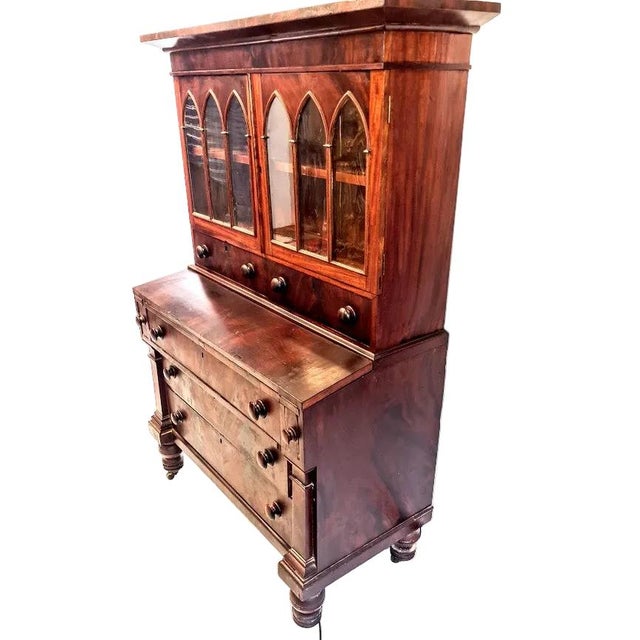 Two piece unit. The upper features a rectangular molded top, over two cabinet doors with Gothic style glass windows...