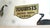 Metal Tourist sign with hand-lettered or stencil-painted double-sided black lettering on a cream background with green...
