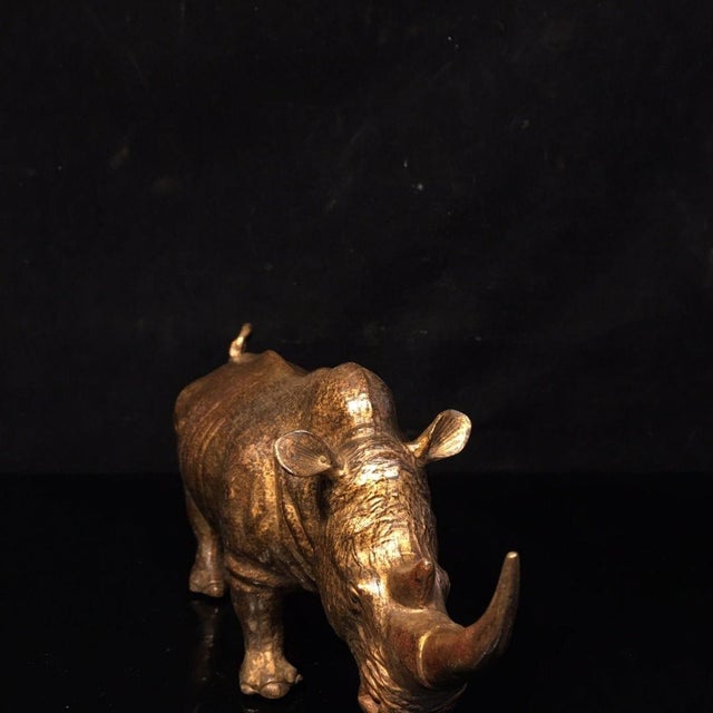 This is a finely crafted antique gilt bronze sculpture of a rhinoceros, captured in a powerful, standing pose with its...