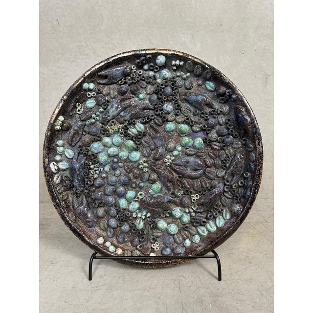 Unique ceramic bowl with distinctive relief decoration, presented on a sturdy metal table stand. Organically inspired...