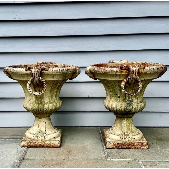A substantial and highly decorative pair of 19th-century cast iron garden urns with figural masks, large pendant ring...