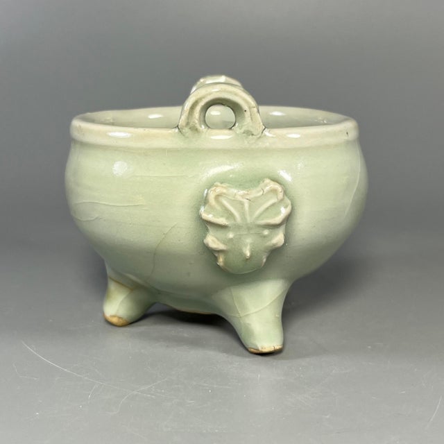 This beautifully crafted celadon tripod censer features two upright handles and embossed floral decoration on the...