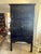 A tall 2 piece stacking cabinet finished in black lacquer featuring vertical bamboo slat panels on the upper and lower...