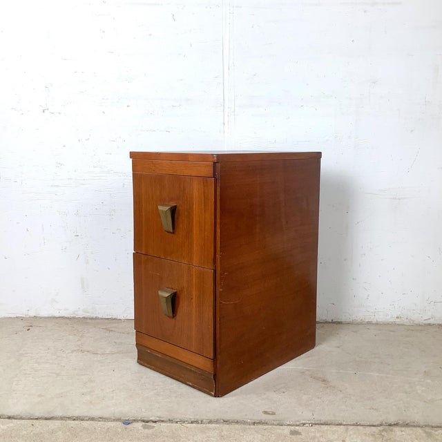 A beautifully scaled vintage American modern two-drawer nightstand featuring warm wood veneer construction and distinctive...