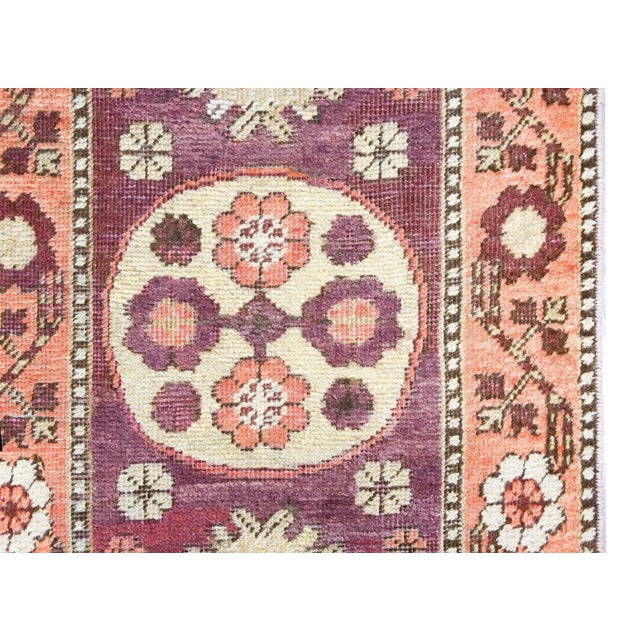 A charming petite early 20th century Central Asian Khotan runner with a mirrored floral pattern containing three floral...