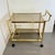 Well-preserved service trolley in golden metal and brown smocked glass tops with wheels. Designed in the Hollywood Regency...