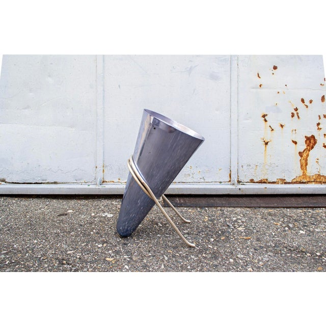 Umbrella stand made of anodized aluminum rod and turned and sheared sheet metal. Designer: Ettore Sottsass Manufacturer:...