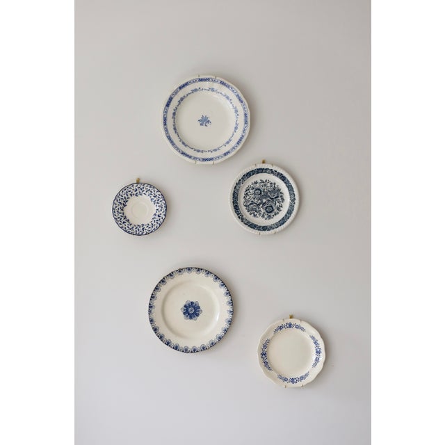 A decorative set of seven earthenware plates, united by a pink theme with floral and pastoral motifs. Each piece features...