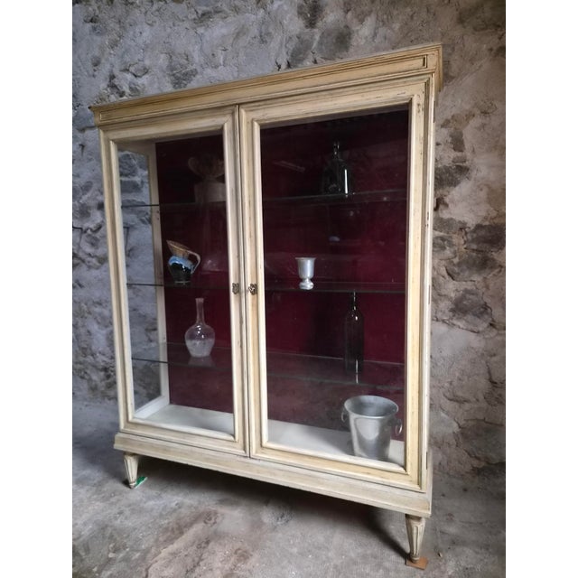 This vintage French display cabinet was originally used in a shop or commercial setting. The cabinet has a cream-painted...