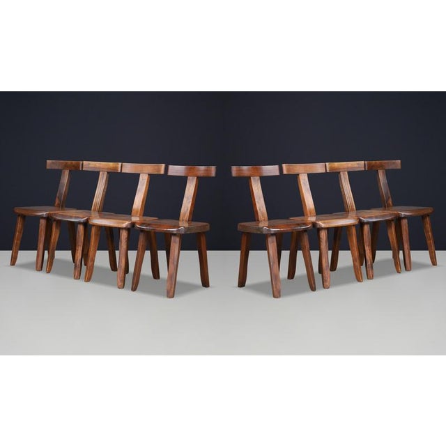 An exceptional and highly sculptural set of eight solid elm “T” dining chairs produced by Aranjou, France, during the...
