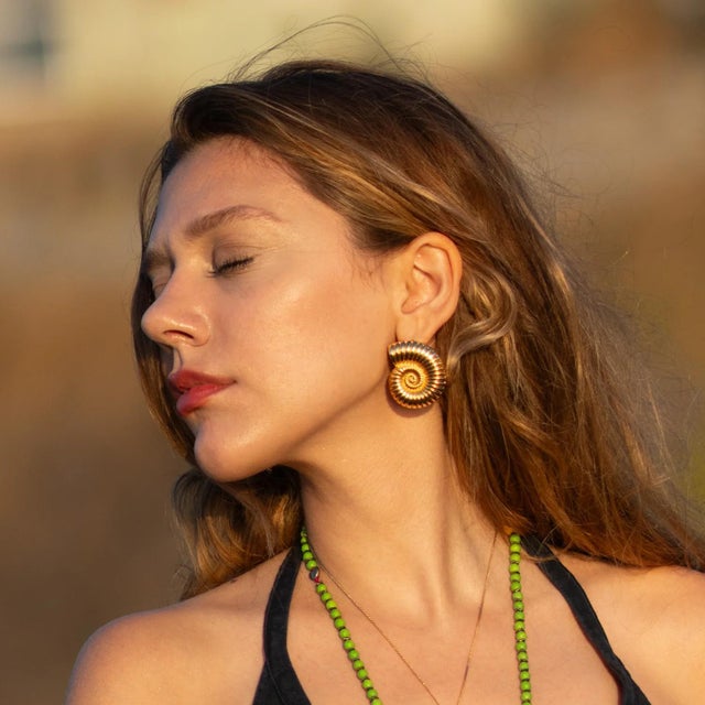 Inspired by the timeless beauty of the sea, these Golden Spiral Seashell Earrings are crafted from bronze and plated with...