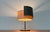 Mid-century table lamp with a movable shade. A minimalist design. The lamp features a simple basic shape with a drum-...