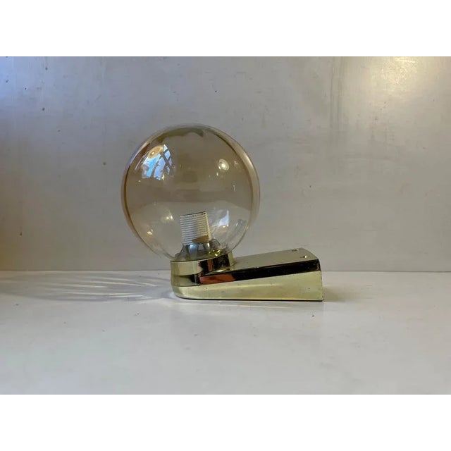 Up or downlight wall light composed of gold chrome plated acrylic mounts and and optically striped amber glass shade....