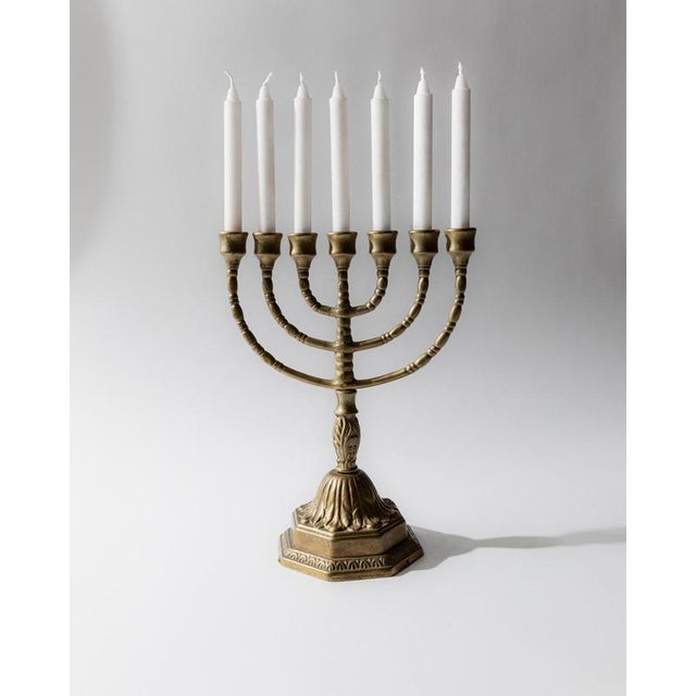 This vintage brass Menorah from the 1950s features a classic seven-arm design enriched with elegant ornamental detailing....