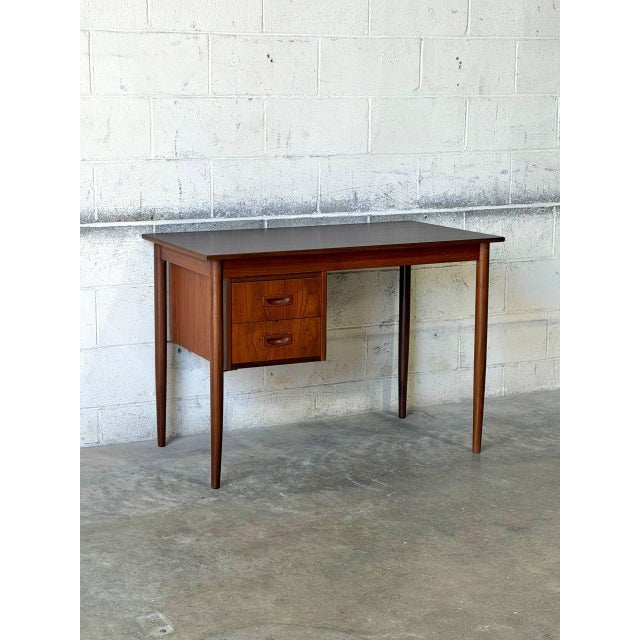 This elegant writing desk features a streamlined rectangular profile elevated by sleek tapered legs. The practical design...