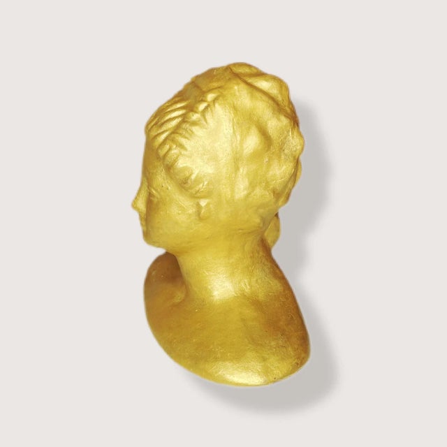 A gold painted (I’m pretty sure) bust of a Roman woman. Classic and timeless in style. Would look nice on a bookshelf, in...
