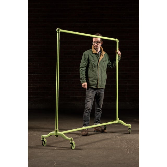 Painted steel garment rack with a simple pipe-frame construction, featuring upright posts joined by a straight hanging bar...