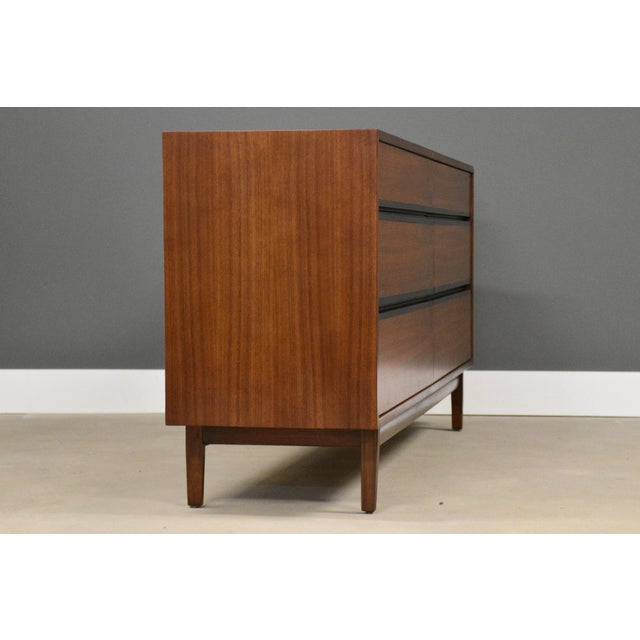 A mid century modern walnut dresser with rosewood drawer pull accents designed by Kipp Stewart for Directional by Calvin....