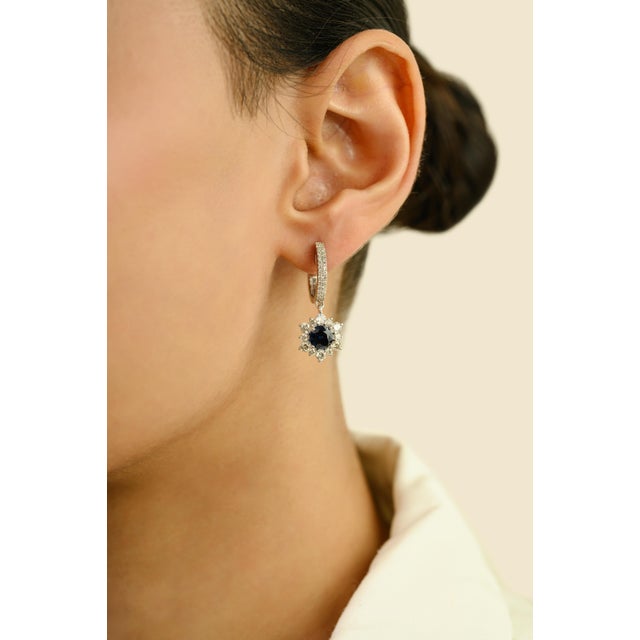These elegant dangle drop earrings feature 2 round cut blue sapphire totaling 1.83 carats, set in rich 14k white gold....