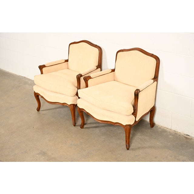 A gorgeous pair of French Provincial Louis XV style bergère lounge chairs By Baker Furniture USA, Circa 1980s Carved...