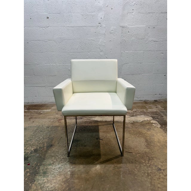 Bright white Naugahyde eco-leather dinging arm chairs on polished chrome bases by Brueton International. Price is per pair...