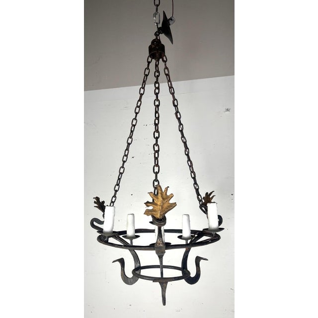 This is a rustic wrought iron chandelier with a medieval-inspired design. It features a circular frame supported by four...