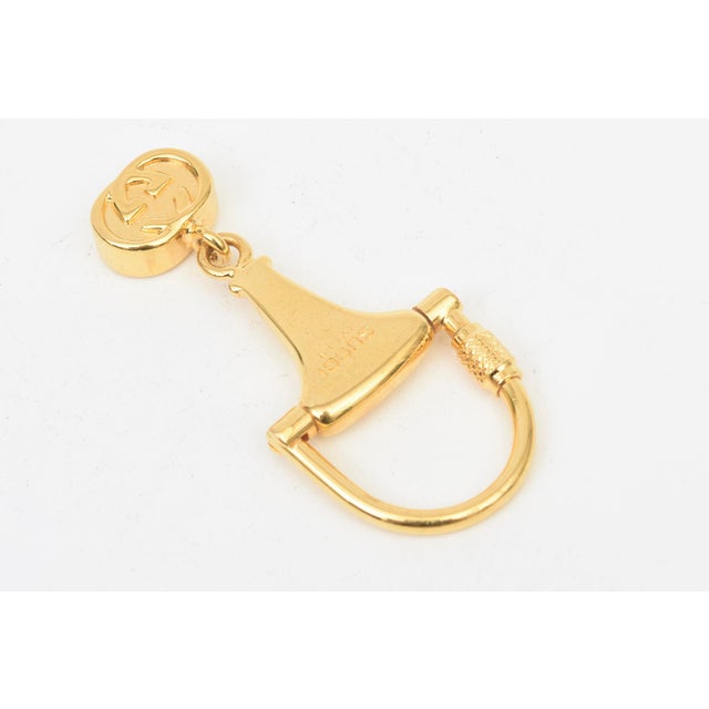 This vintage Gucci gold plated key chain is of the horse bit. the interlocking pendant at the bottom is the double GG"s....