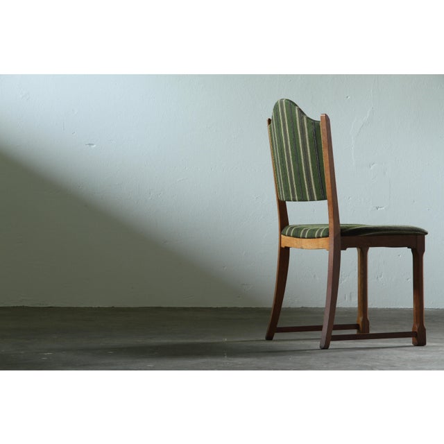 A set of four slim oak dining chairs from the mid-20th century. These chairs have a light and elegant presence, with...