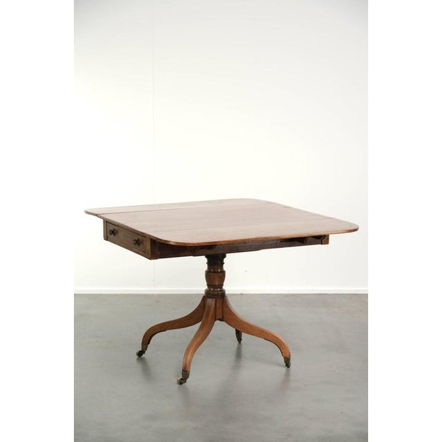 This antique English drop-leaf side table dates from the 19th century and features beautiful brass handles. Side tables...