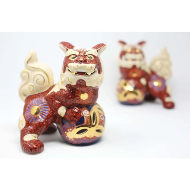 An opposing pair of ceramic male/female foo lions, hand-painted in the Satsuma style with gold accents. Notice the subtle...