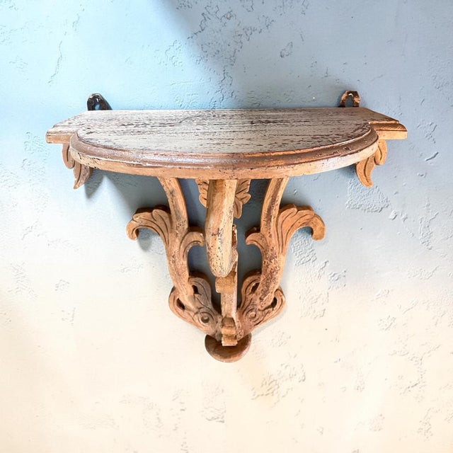 Elegant vintage Florentine-style carved wood wall shelf featuring an architectural demilune top supported by elaborate...