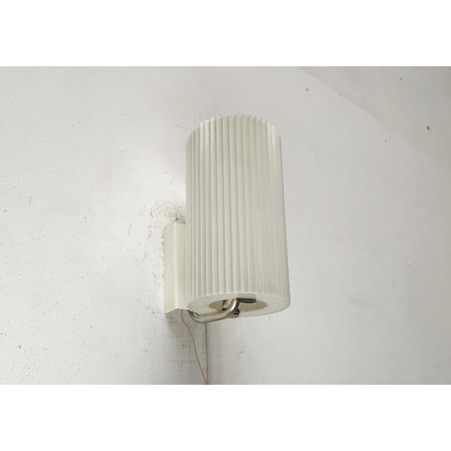 Rare wall light from Erco. A minimalist design. The cylindrical shade is made of plastic. It features a ribbing all...