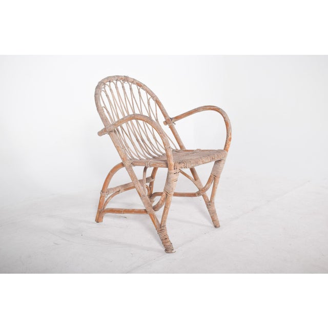 Wicker chair with arms. with a high backrest and natural wicker structure, revealing an organic and artisanal design. The...