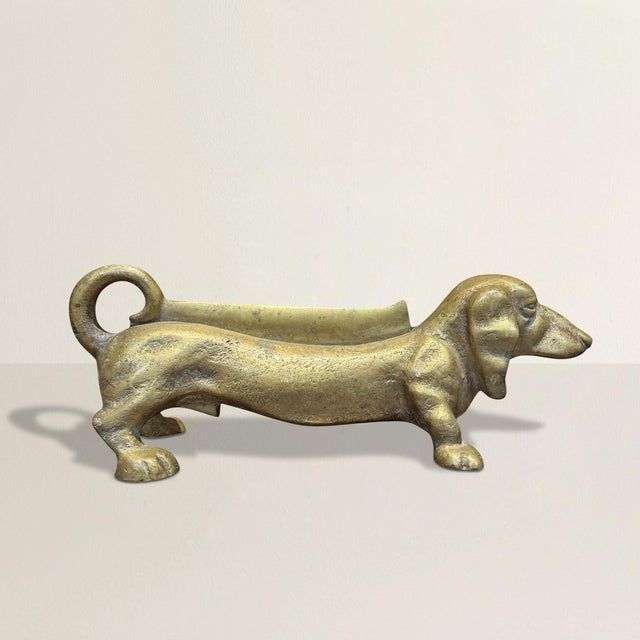 This early 20th-century American cast brass boot scrape takes the delightful form of a Dachshund, blending functionality...